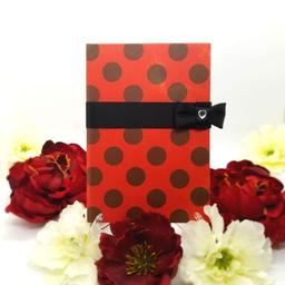 Red book with black spots and a ribbon clasp